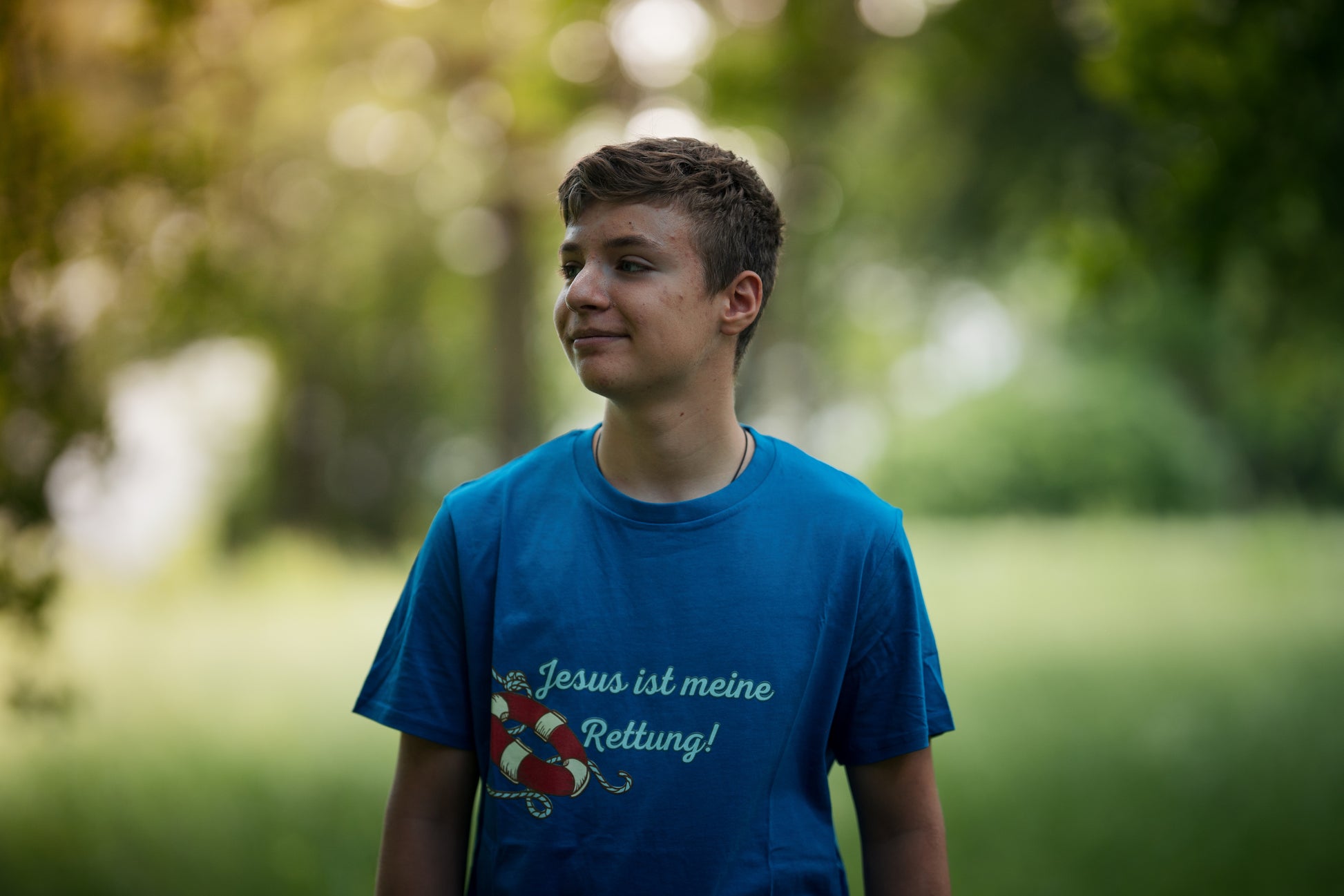 christliches T-Shirt mit einem Unisex-Schnitt in blau aus 100 % Bio-Baumwolle an einem Model auf der Vorderseite mittig auf der Brust "Jesus ist meine Rettung!" mit einem Rettungsring. Erhältlich in den Größen S bis XXL