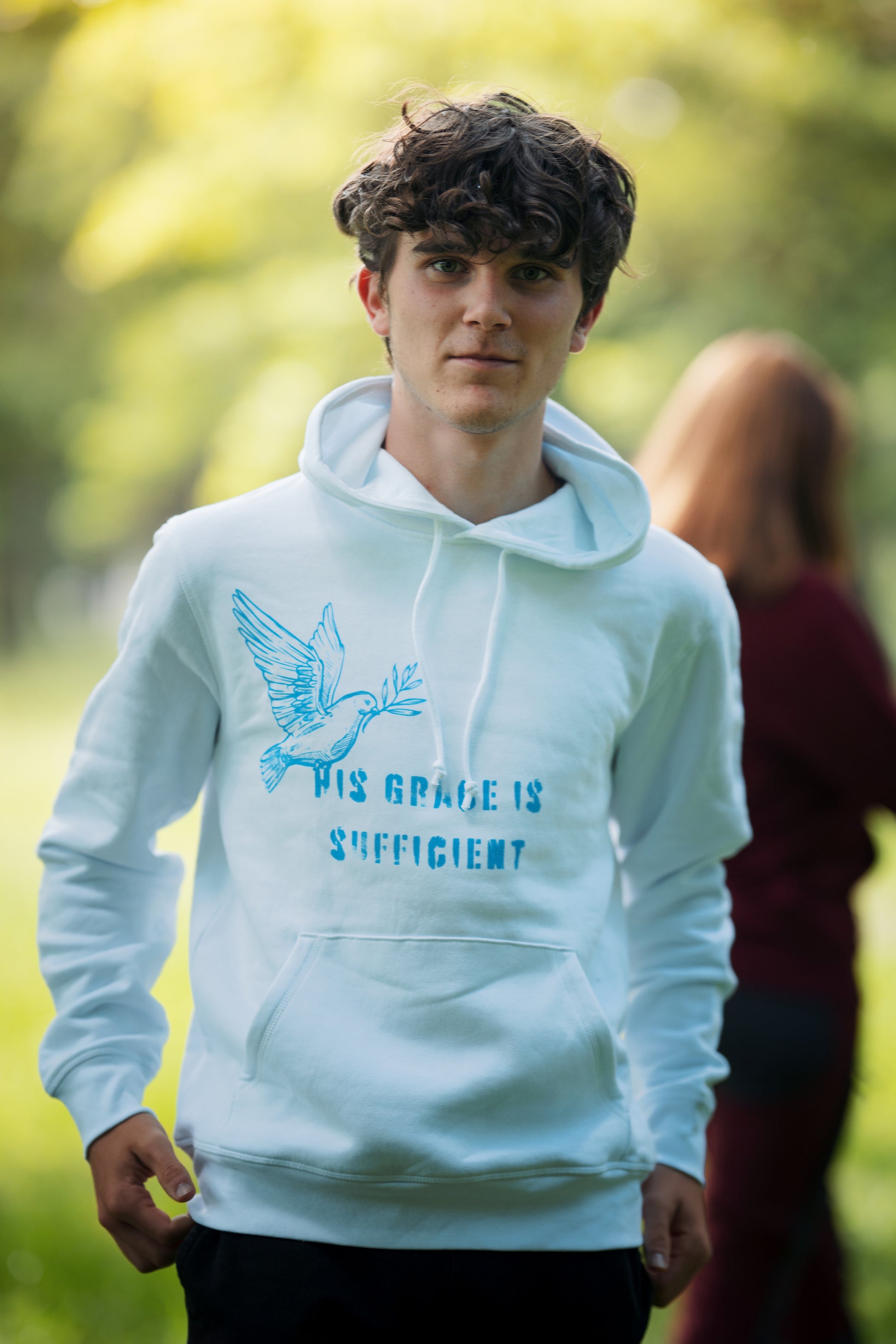 Ein Model mit einem weißen Hoodie "His grace is sufficent" .