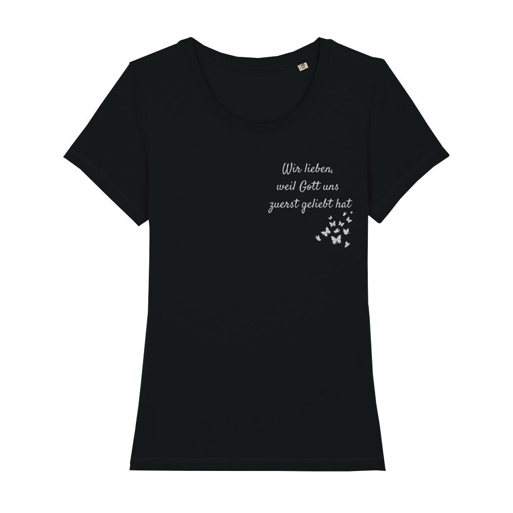 christliches T-Shirt mit einem Frauen-Schnitt in schwarz aus 100 % Bio-Baumwolle "Wir lieben weil Gott uns zuerst geliebt hat" rechts auf der Brust. Erhältlich in den Größen XS bis XXL